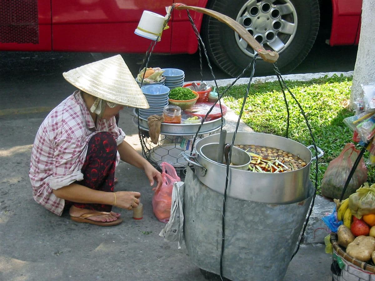 Người phụ nữ đội nón lá bên gánh hàng ăn sáng trên vỉa hè